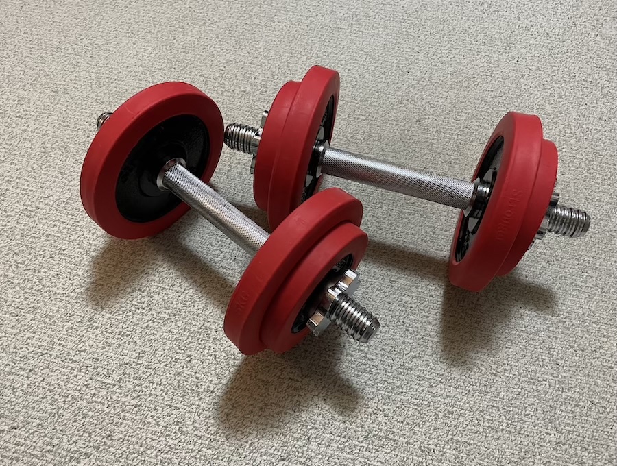 20年以上使い続けてきた古い赤いダンベル。剥げた塗装や小さな傷が、トレーニングの歴史を物語っている。